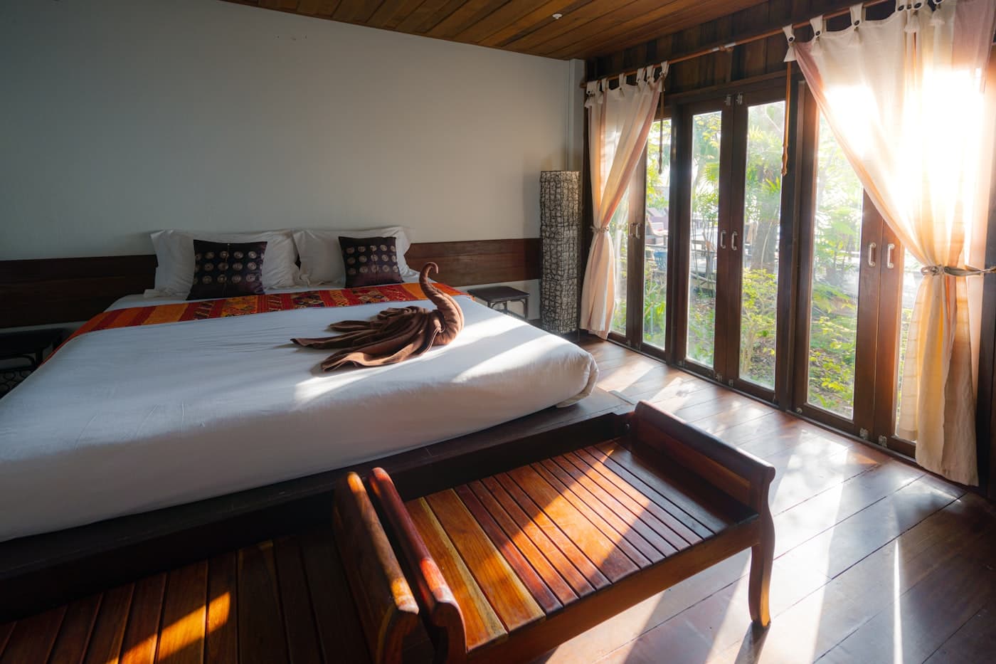 A sunlit hotel suite with wooden floors and garden views
